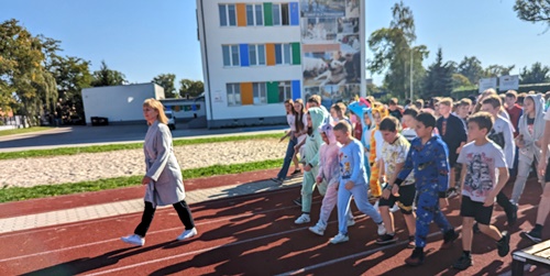 dzieci w piżamach biegną po bieżni boiska szkolnego